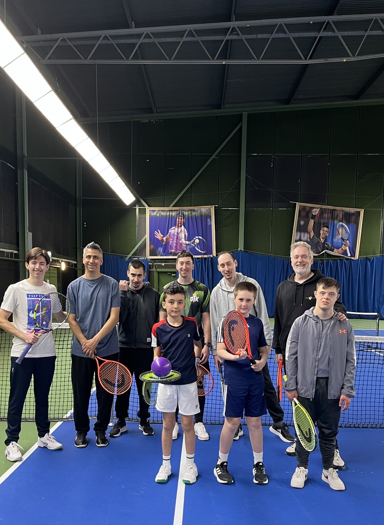 Spelare i sportrullstol skrattar på en tennisbana