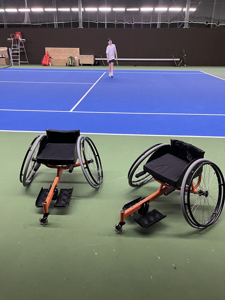 Glad spelare i sportrullstol på en tennisbana